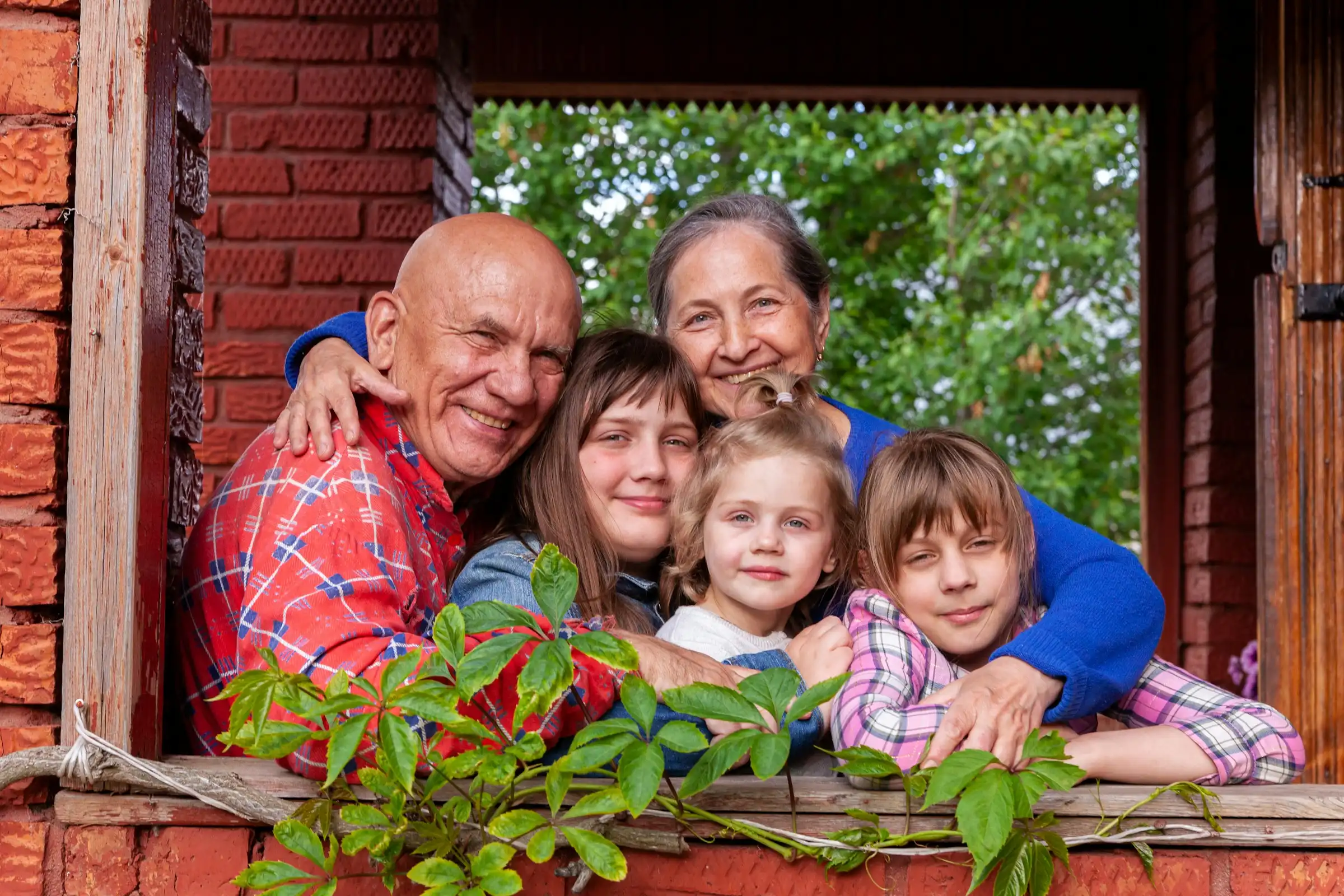 Grandparents and grandchildren smiling together on a brick front porch
