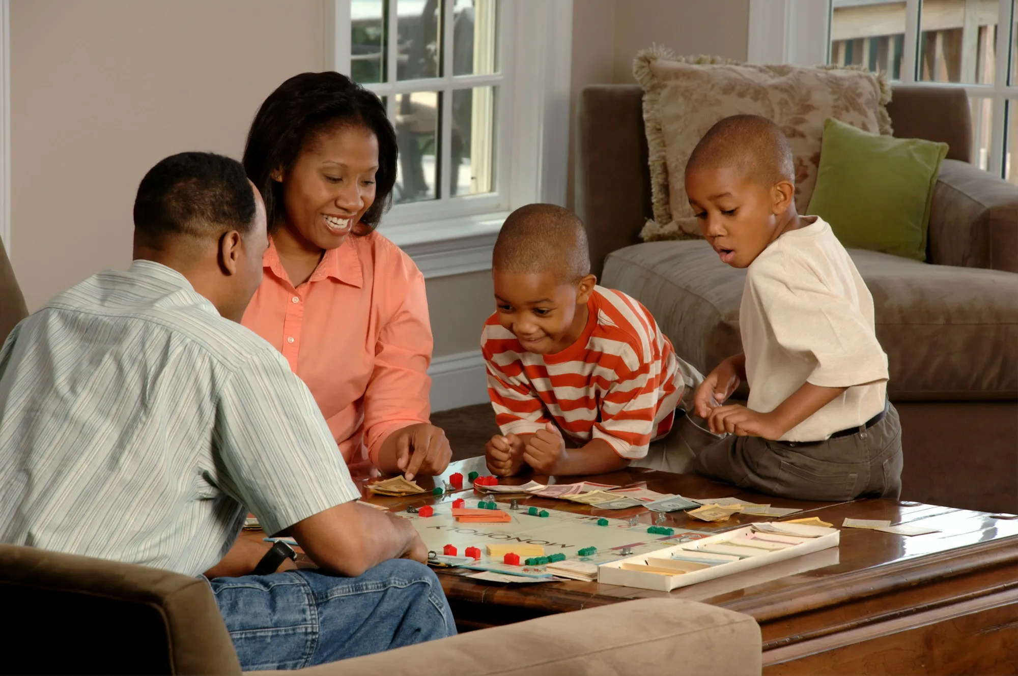Parents and two sons playing a board game together in their living room